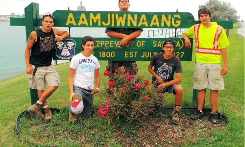 public works students in front of aamjiwnaang signpublic works students in front of aamjiwnaang sign